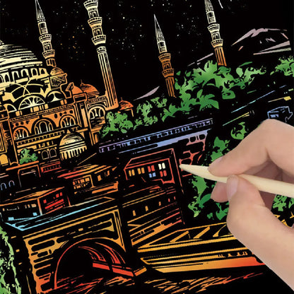 Hand holding a stylus over a Scratch Art cityscape with illuminated buildings.